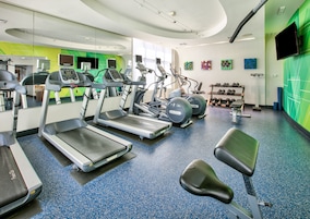 Un gimnasio con cintas de correr, elípticas y pesas sueltas.