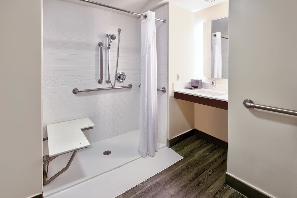 A bathroom with a shower, a sink, and a mirror.