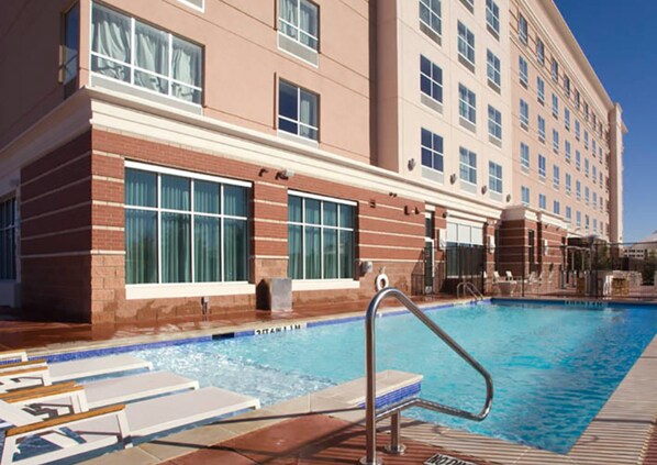 Un hotel con piscina, ventanas amplias y fachada de ladrillo.