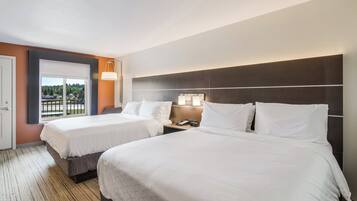 A hotel room with two beds, a large window with a view, and a nightstand with a lamp.