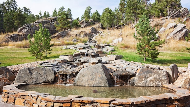 A natural outdoor setting with a small waterfall, a pond, and surrounding trees. - Holiday Inn Express Hotel & Suites Custer by IHG (Custer)