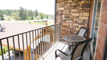 A balcony with a stone wall, a round table, and two chairs.