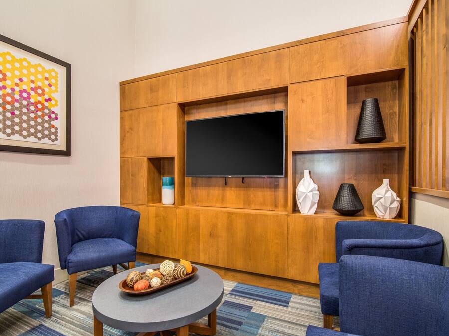 Una sala de estar moderna con un televisor de pantalla plana, paneles de madera y sillones tapizados en azul.