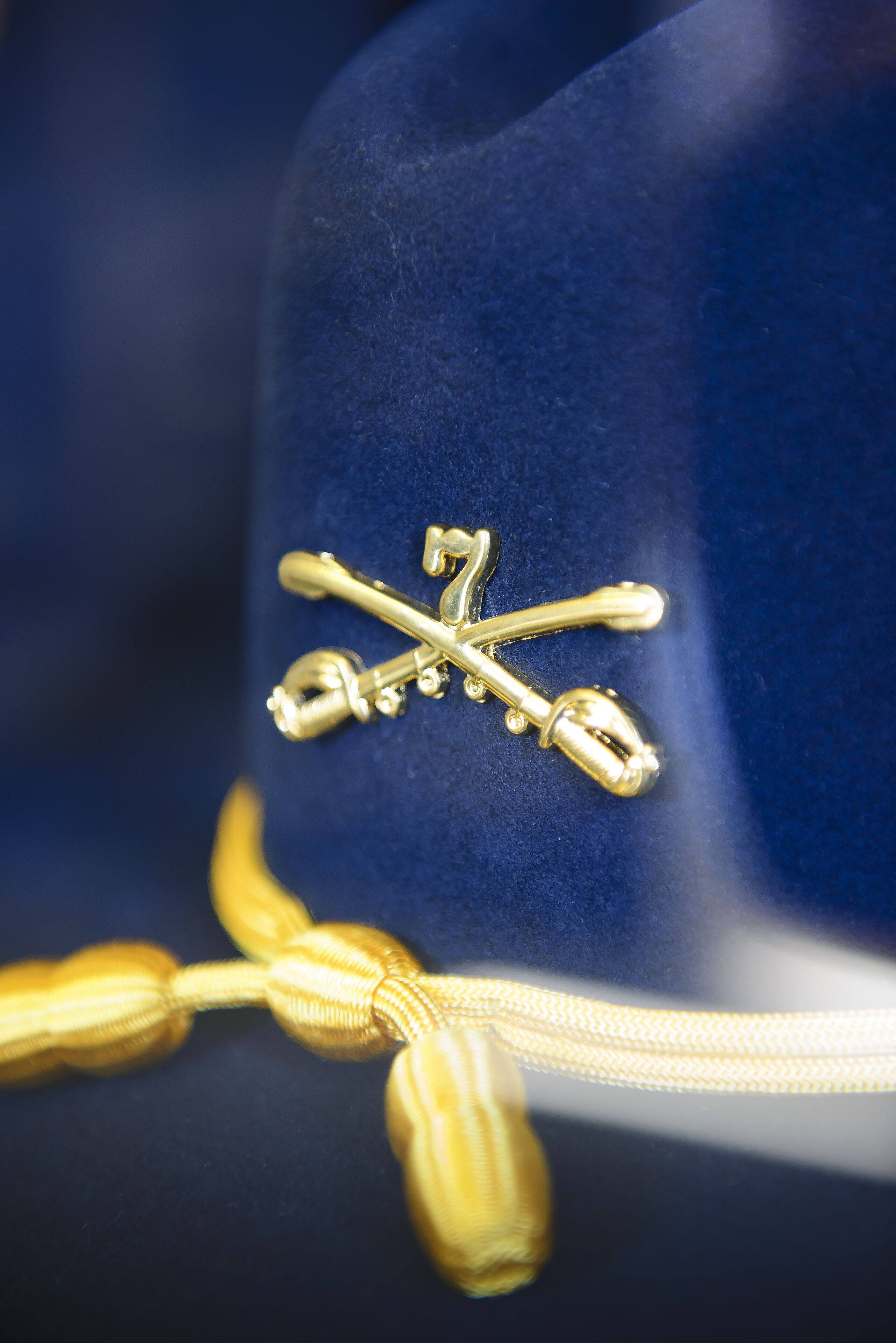 Um close-up de um chapéu azul com um emblema dourado e uma fita amarela.
