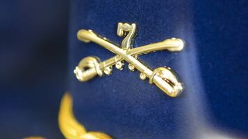 Um close-up de um chapéu azul com um emblema dourado e uma fita amarela.