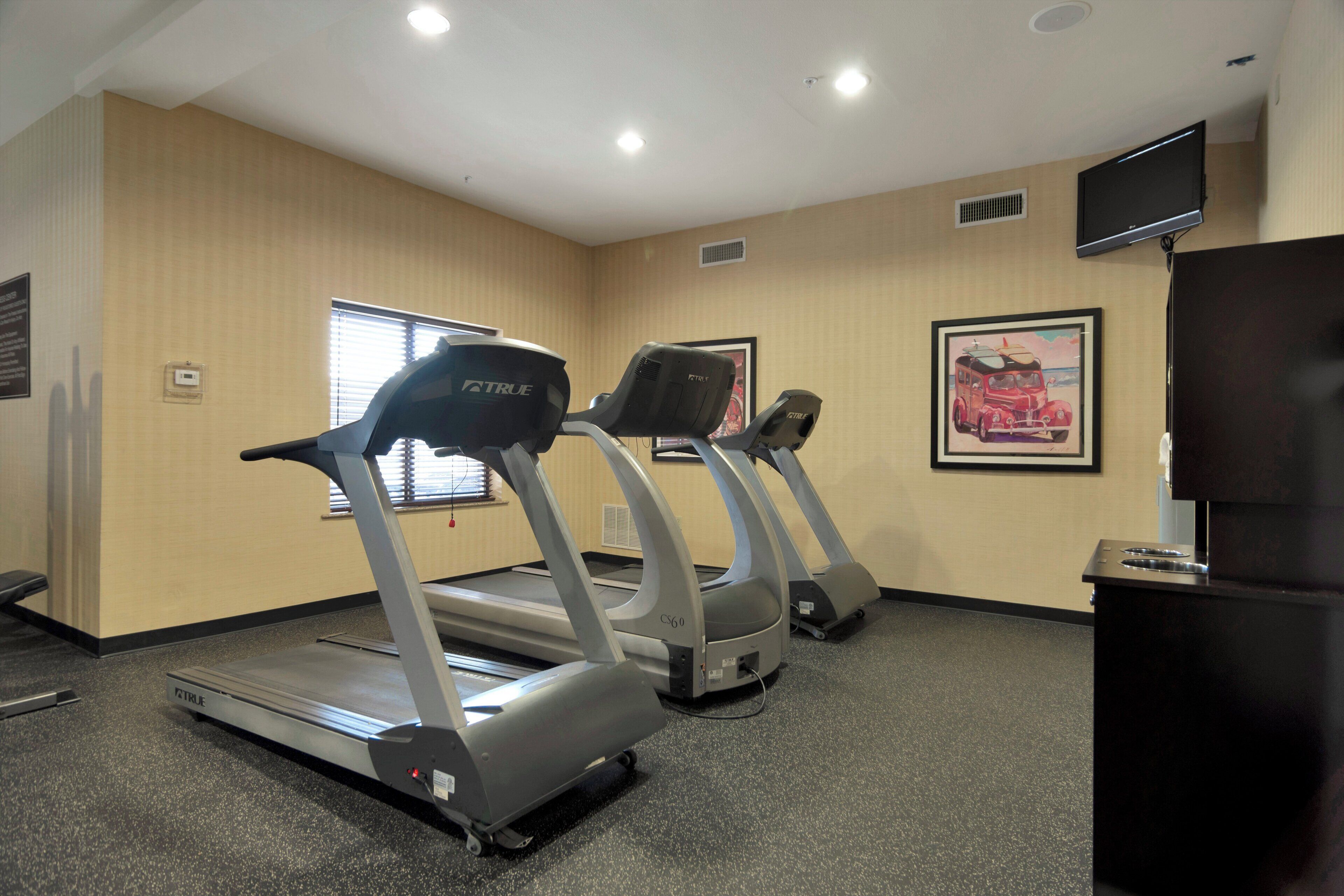 Un gimnasio con cintas de correr y una televisión.