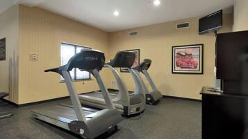 Un gimnasio con cintas de correr y una televisión.
