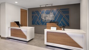 Un mostrador de recepción de diseño moderno, con un panel de madera y una obra de arte geométrica azul en la pared.