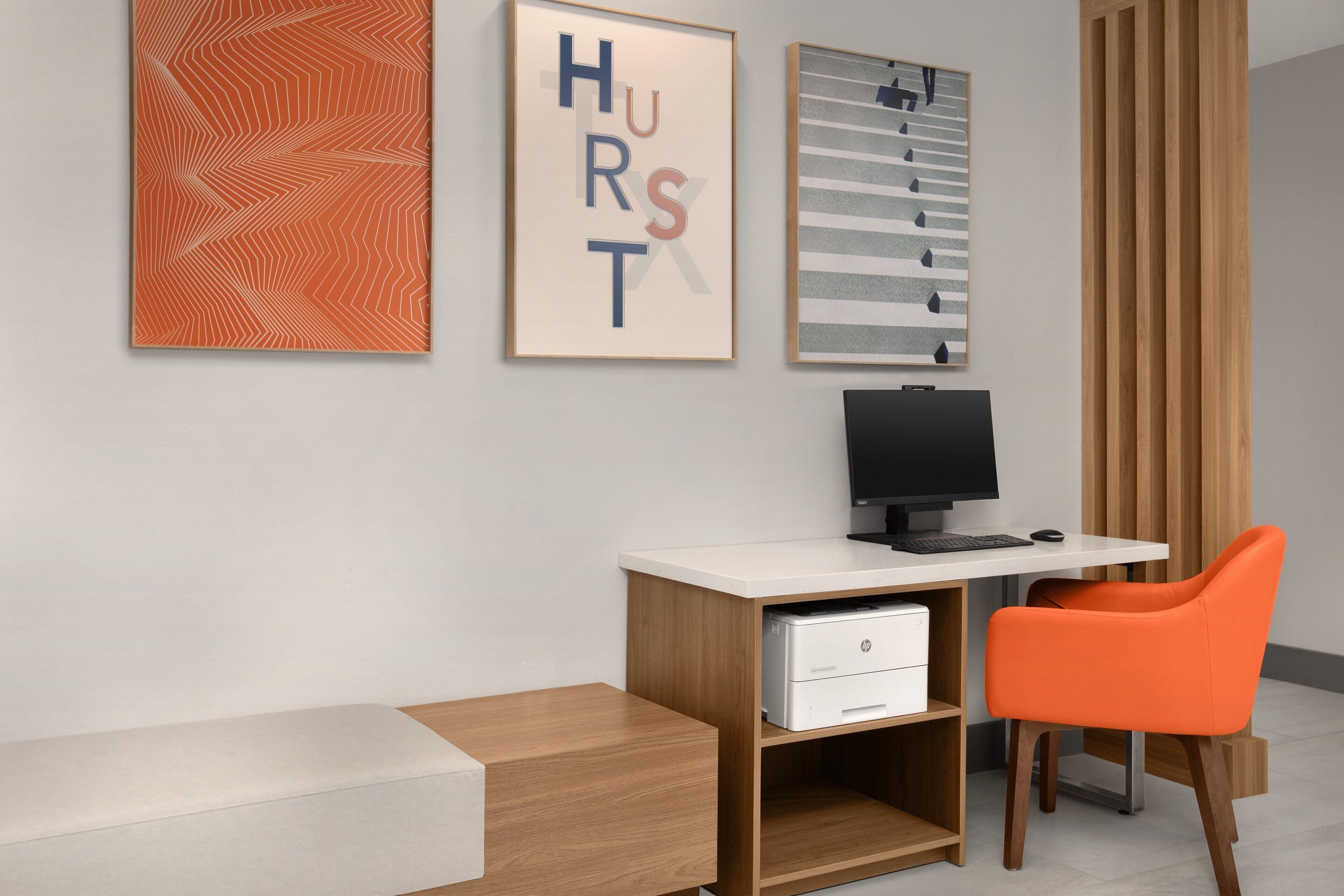 A modern office with a desk, computer, and orange chair.