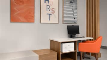 A modern office with a desk, computer, and orange chair.