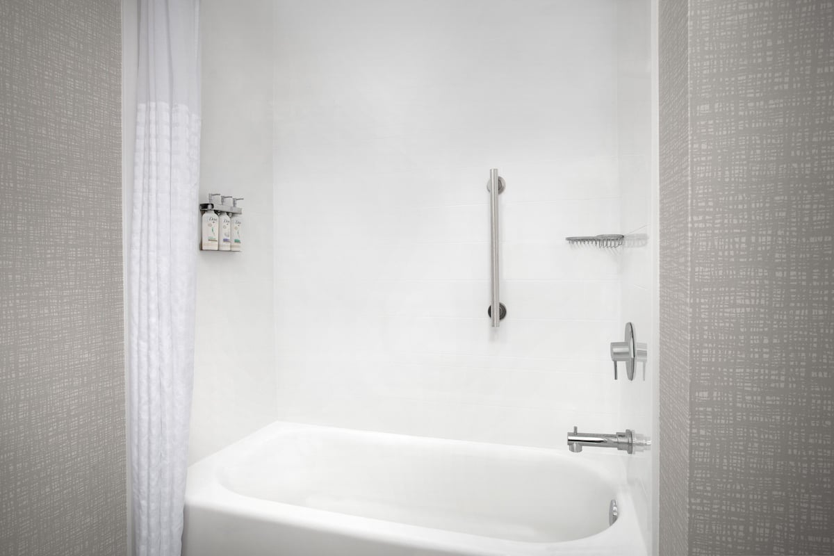 Un baño moderno con una bañera blanca, un cabezal de ducha de mano y un grifo empotrado.