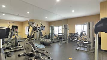A gym with various exercise equipment including treadmills, elliptical machines, and free weights.