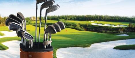 A golf bag with multiple clubs on a golf course.