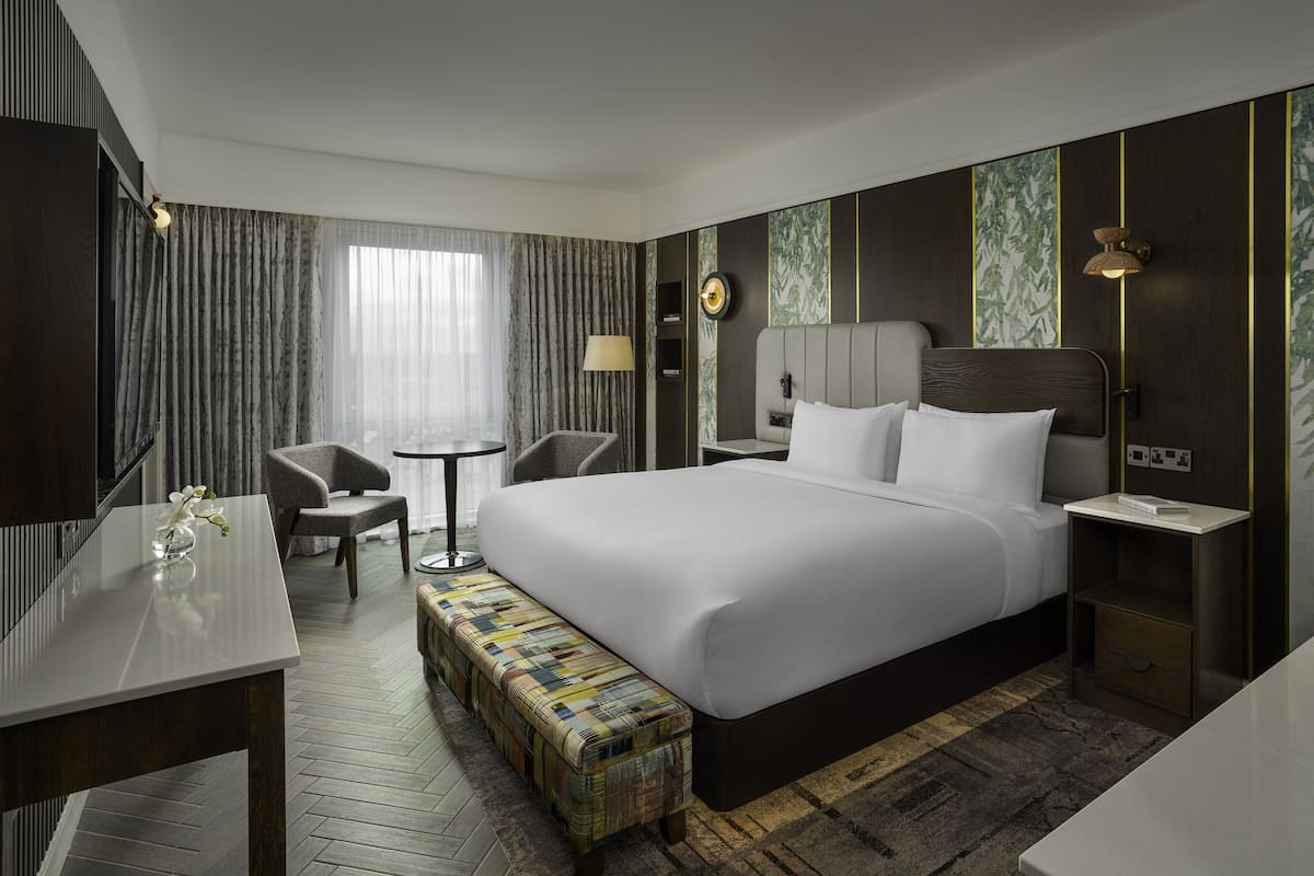 Una habitación de hotel moderna con una cama grande, un escritorio pequeño, una silla y un banco.