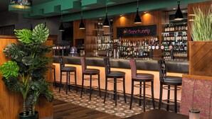 A bar area with a wooden counter, multiple stools, and a variety of bottles. - Crowne Plaza Hotel Blanchardstown by IHG (Dublin)