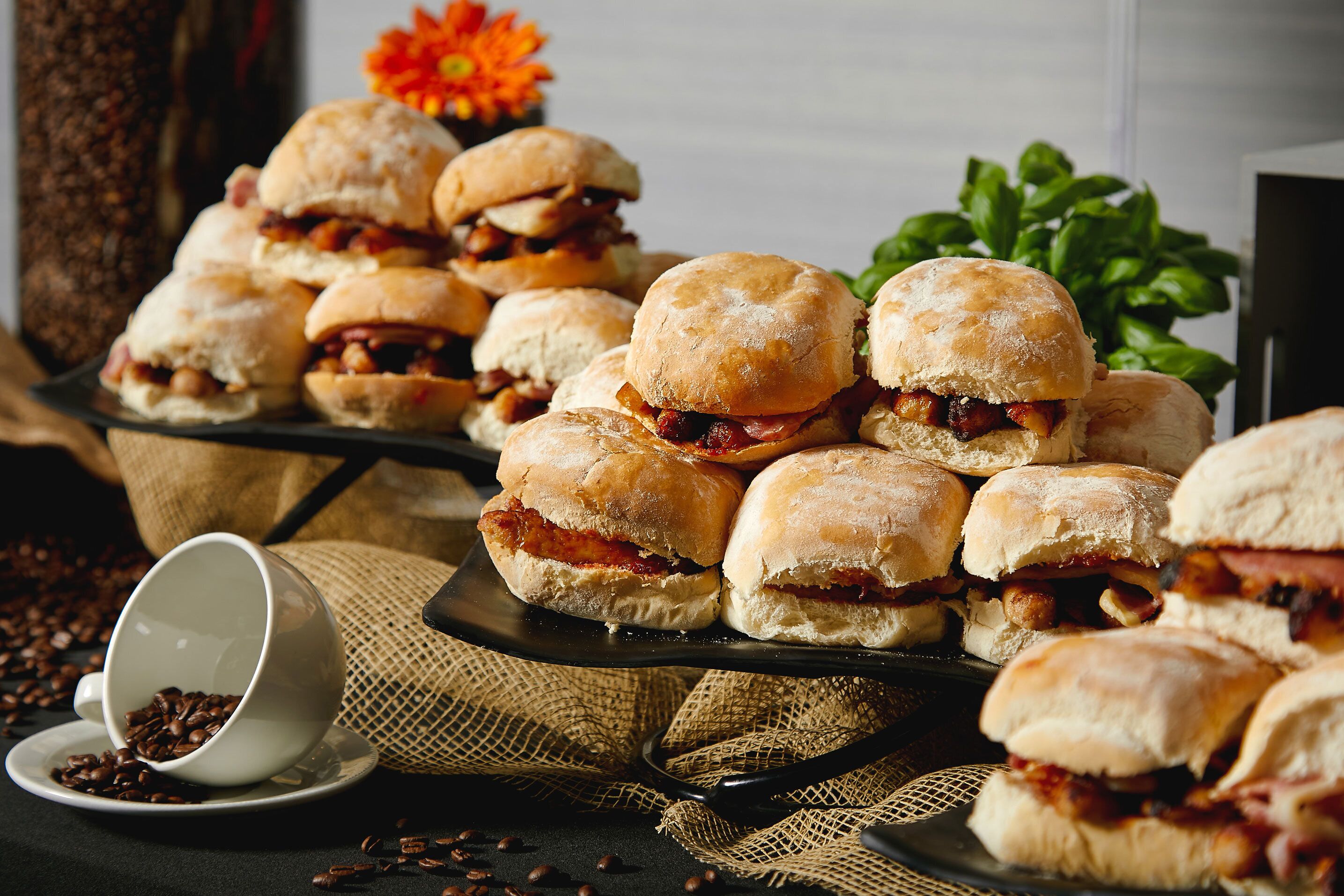 A tray of sandwiches with a cup of coffee and scattered coffee beans.
