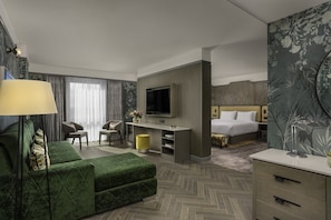 A hotel room with a green sofa, a TV, a bed, a desk, and a chair. - Crowne Plaza Hotel Blanchardstown by IHG (Dublin)