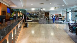 A modern hotel lobby with a reception desk, a staircase, and a seating area. - Crowne Plaza Hotel Blanchardstown by IHG (Dublin)