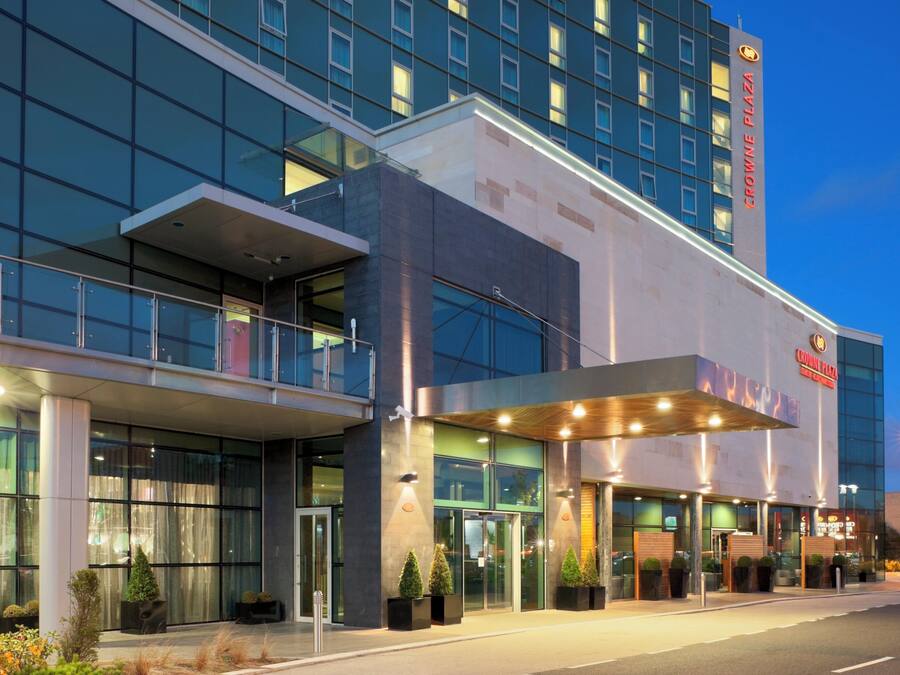 Un hotel moderno con fachada de vidrio, un letrero destacado que dice 'Crowne Plaza' y una entrada bien iluminada.