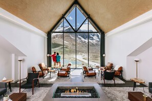 Un amplio salón con una gran ventana que ofrece vistas a la montaña, chimenea y muebles modernos.