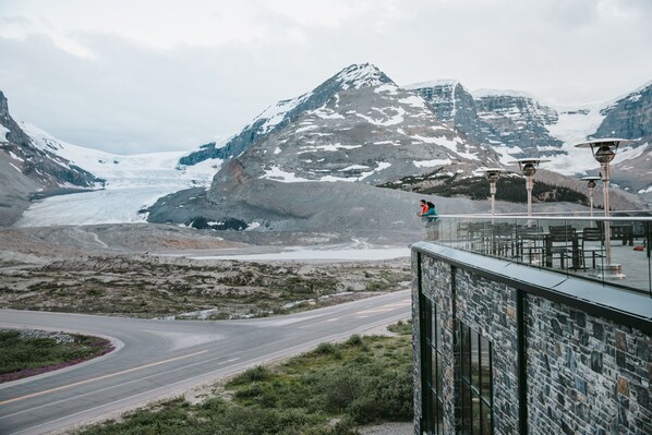 Un edificio moderno con fachada de vidrio que ofrece vistas a un paisaje montañoso con un glaciar.