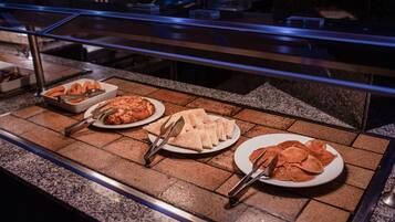 Mostrador de buffet con diversos alimentos y utensilios para servir.