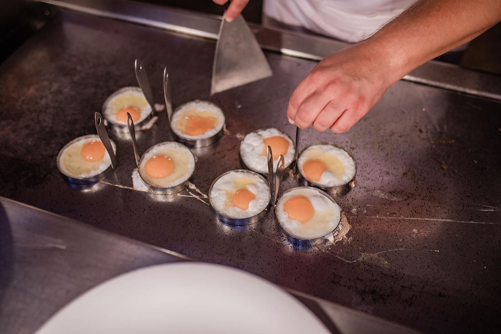 A person cooking eggs on a griddle.