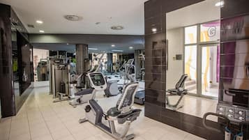 Un gimnasio moderno con diversos equipos de ejercicio, incluyendo cintas de correr, bicicletas estáticas y máquinas de pesas.