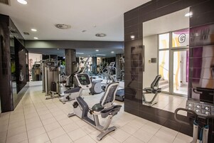 Un gimnasio moderno con diversos equipos de ejercicio, incluyendo cintas de correr, bicicletas estáticas y máquinas de pesas.