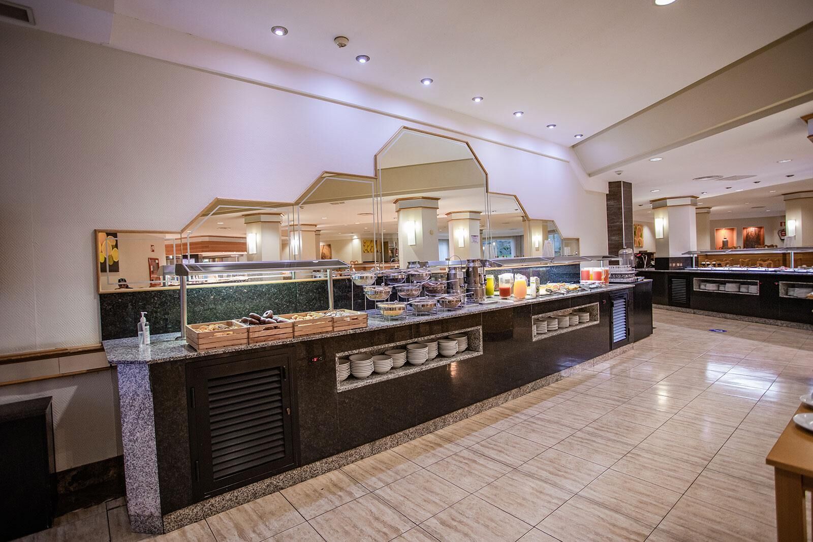 A buffet area with a marble counter, various food items, and a mirror above.