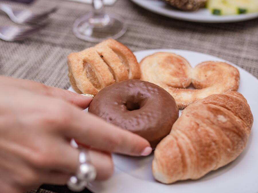 A breakfast plate with croissants, a chocolate donut, and a glass of orange juice.