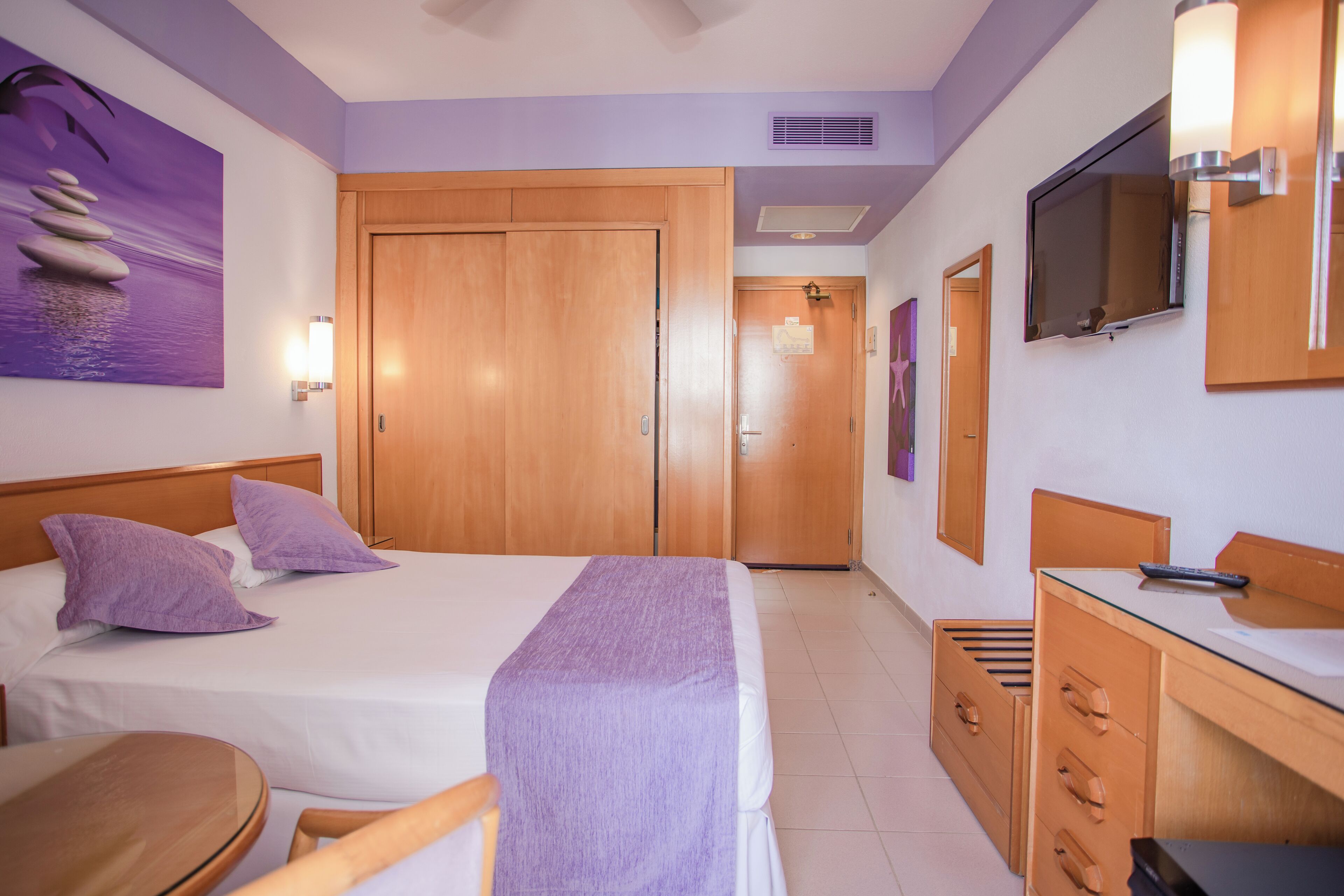 Une chambre d’hôtel avec un lit, un bureau, une chaise, une télévision et une porte de salle de bain.