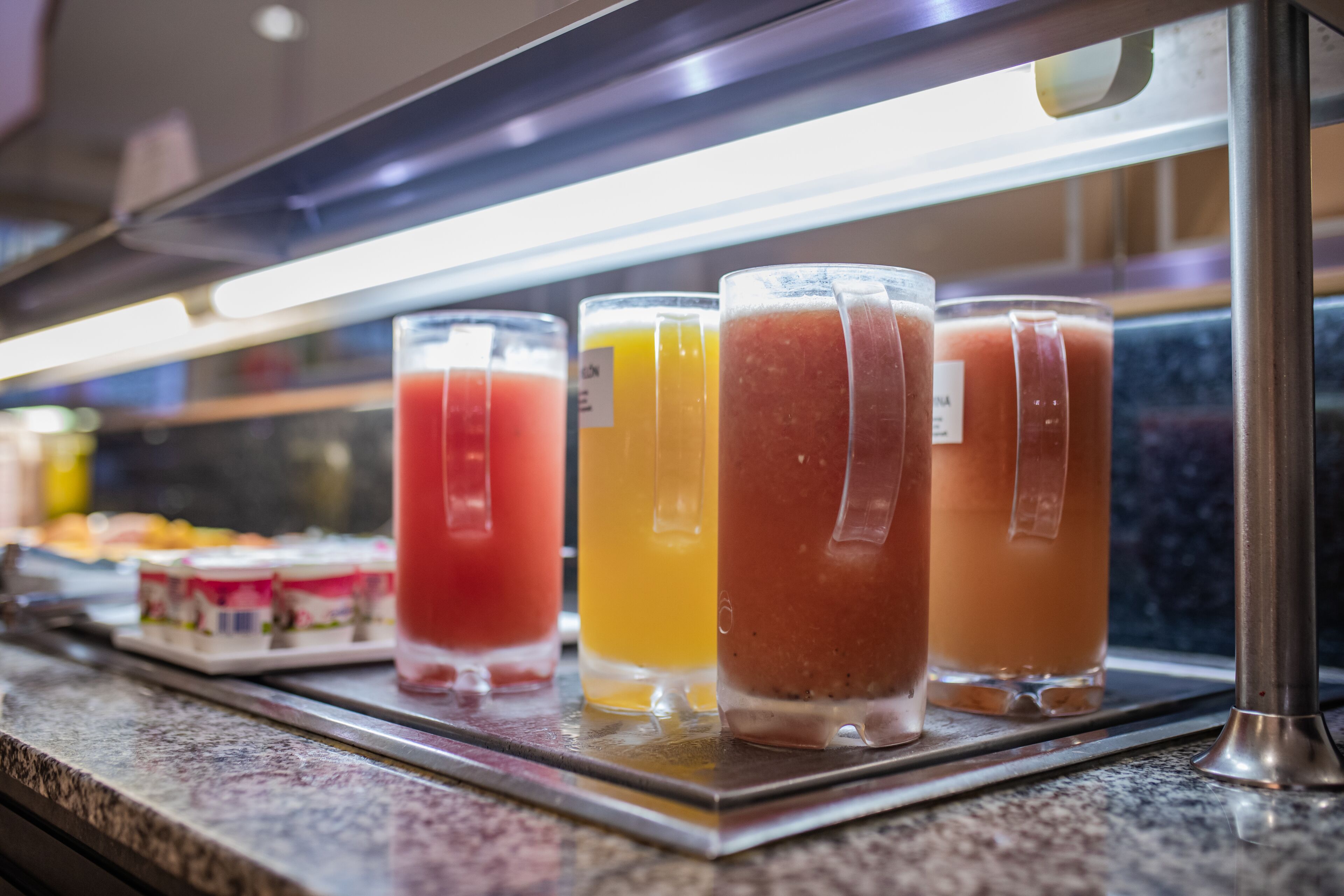 A display case with various beverages, including juices and smoothies, arranged on a countertop.