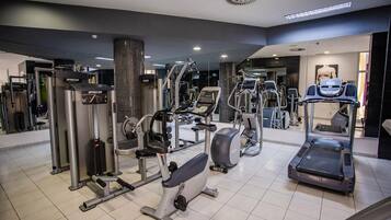 Ein modernes Fitnessstudio mit verschiedenen Trainingsgeräten, darunter Laufband, Crosstrainer und Kraftgeräte.