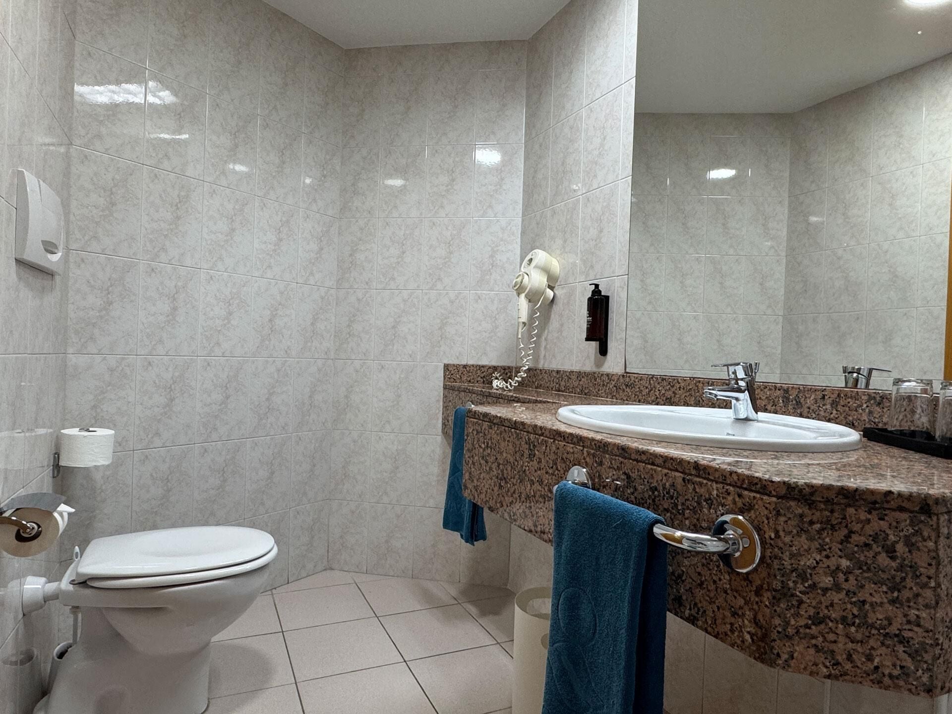 A bathroom with a toilet, sink, and mirror.
