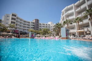 Una piscina al aire libre, sombrillas, sillones reclinables de piscina