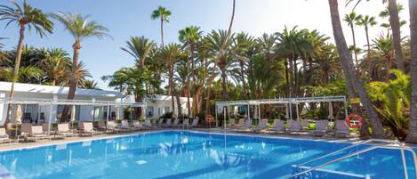 Una piscina con sillas de descanso y palmeras.
