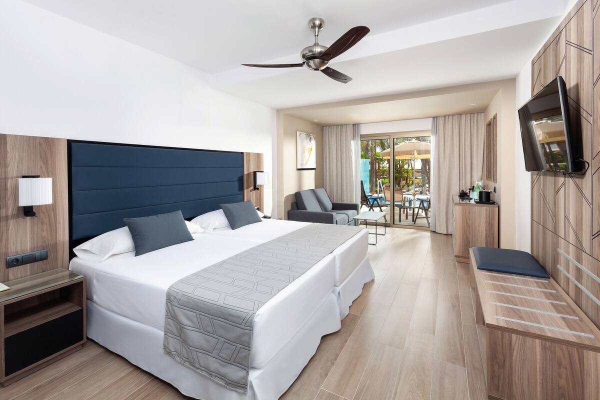 Een moderne hotelkamer met een groot bed, een bureau, een stoel, een televisie en een balkon met uitzicht.