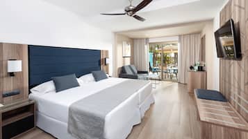 Una habitación de hotel moderna con una cama grande, un escritorio, una silla, un televisor y un balcón con vistas.