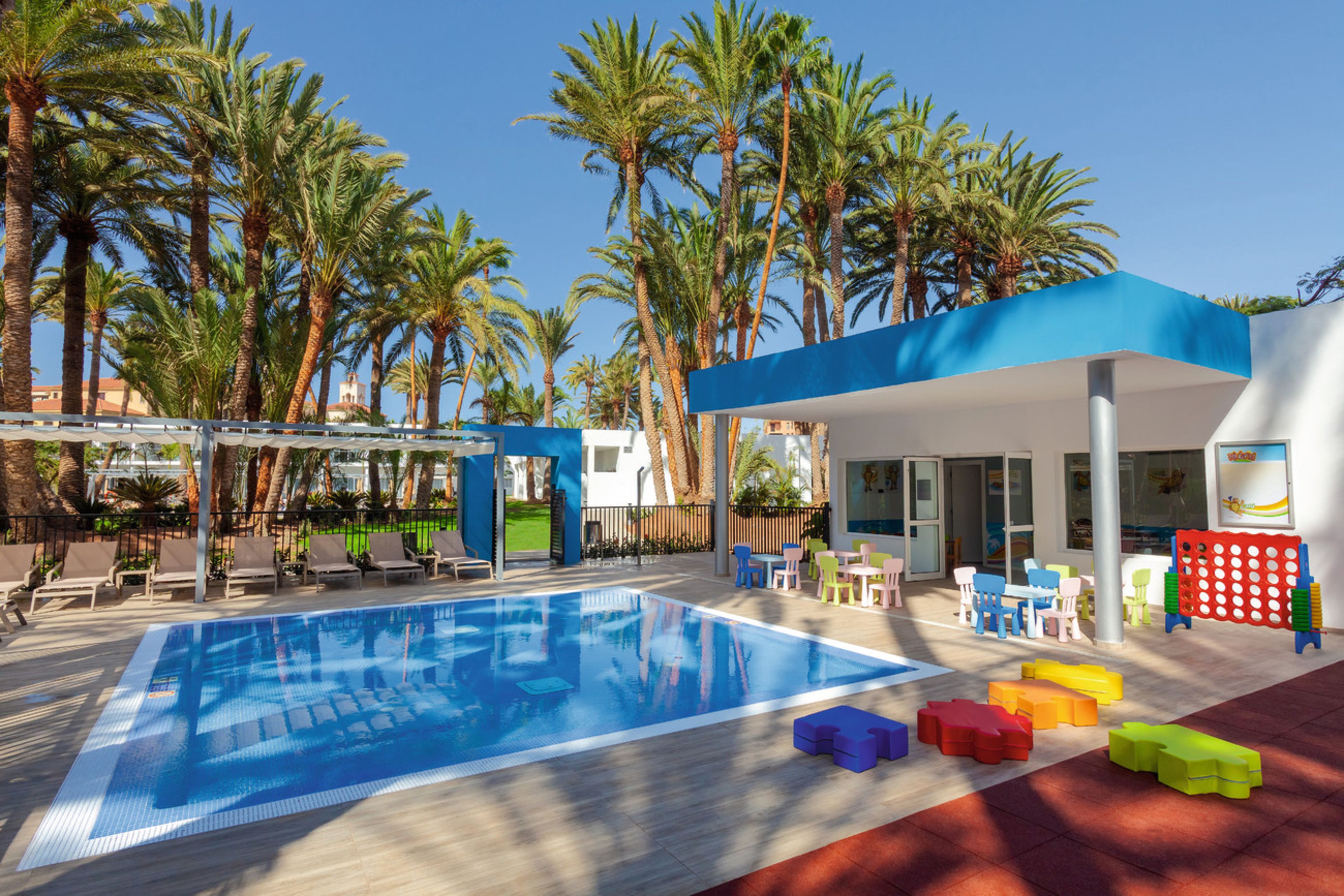A swimming pool with lounge chairs and a children's play area with colorful blocks.