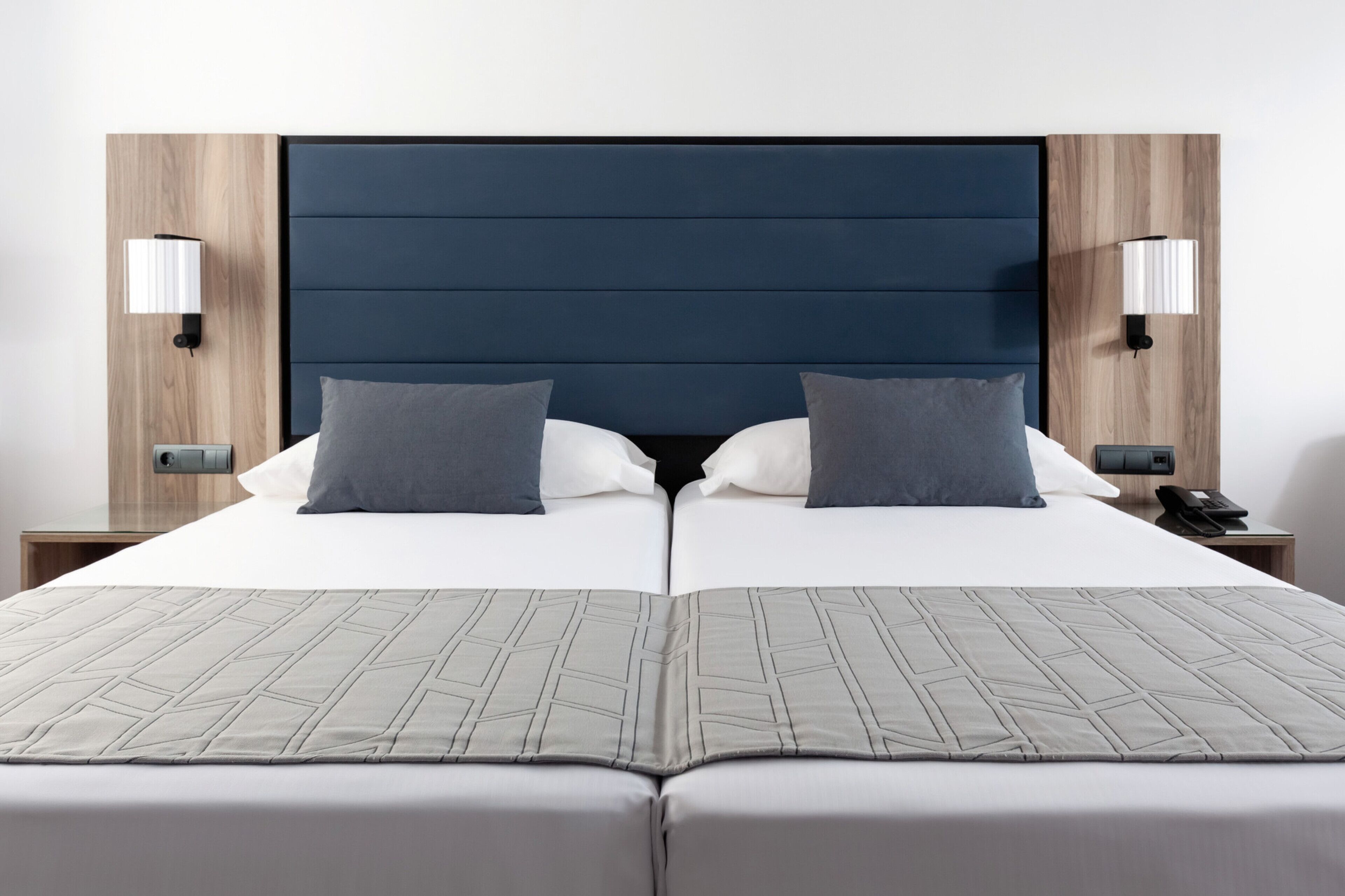 A double bed with a dark headboard, two bedside lamps, and a neutral-toned bedspread.