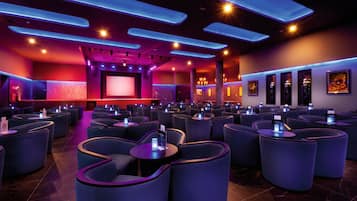 Un cine moderno con butacas dispuestas en hileras curvas, una pantalla grande e iluminación ambiental.