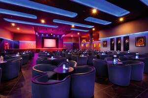 Un cine moderno con butacas dispuestas en hileras curvas, una pantalla grande e iluminación ambiental.
