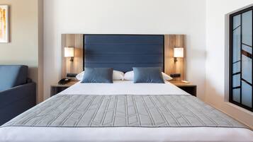 A hotel room with a large bed, two bedside tables, a nightstand, a chair, and a window with a view.