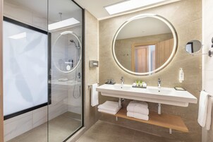 A modern bathroom with a glass-enclosed shower, a large mirror, and a vanity with a sink and towel rack.