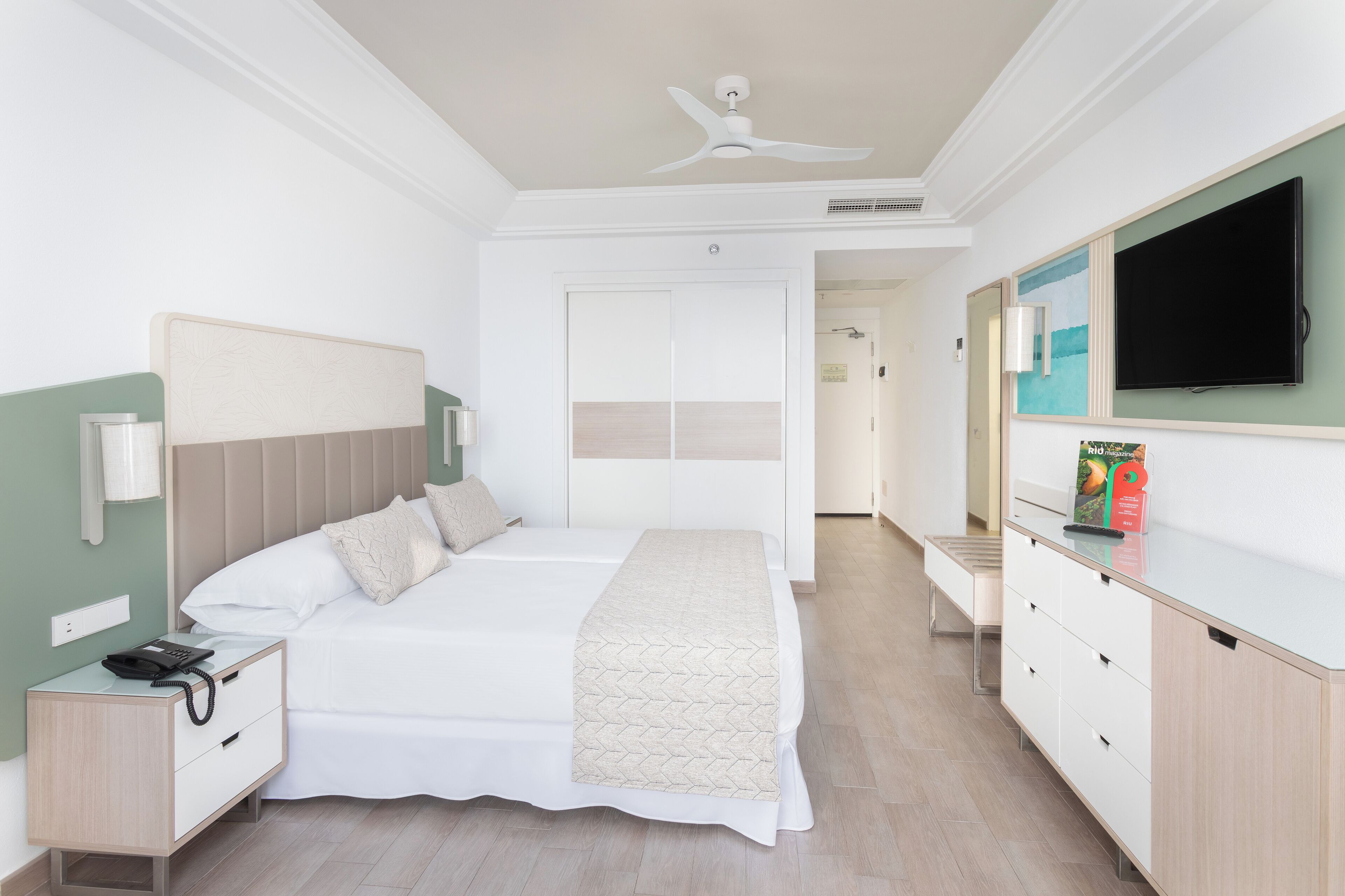Una habitación de hotel con cama, mesita de noche, televisor y cómoda.