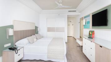 Una habitación de hotel con cama, mesita de noche, televisor y cómoda.