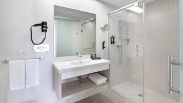 Un baño moderno con cabina de ducha de vidrio, un lavabo blanco y un espejo grande.