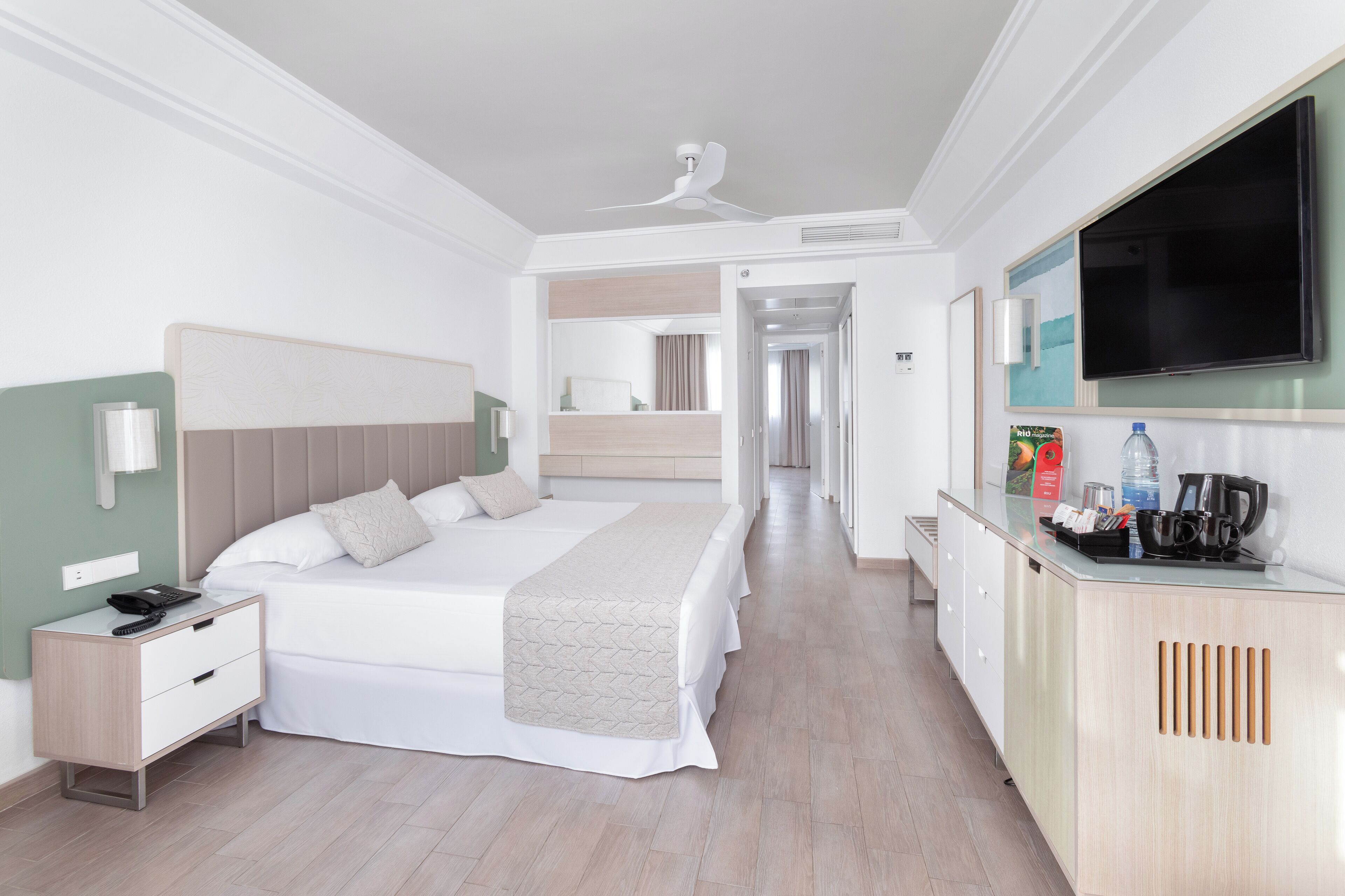 Habitación de hotel con cama, mesita de noche, televisión y una zona de kitchenette.