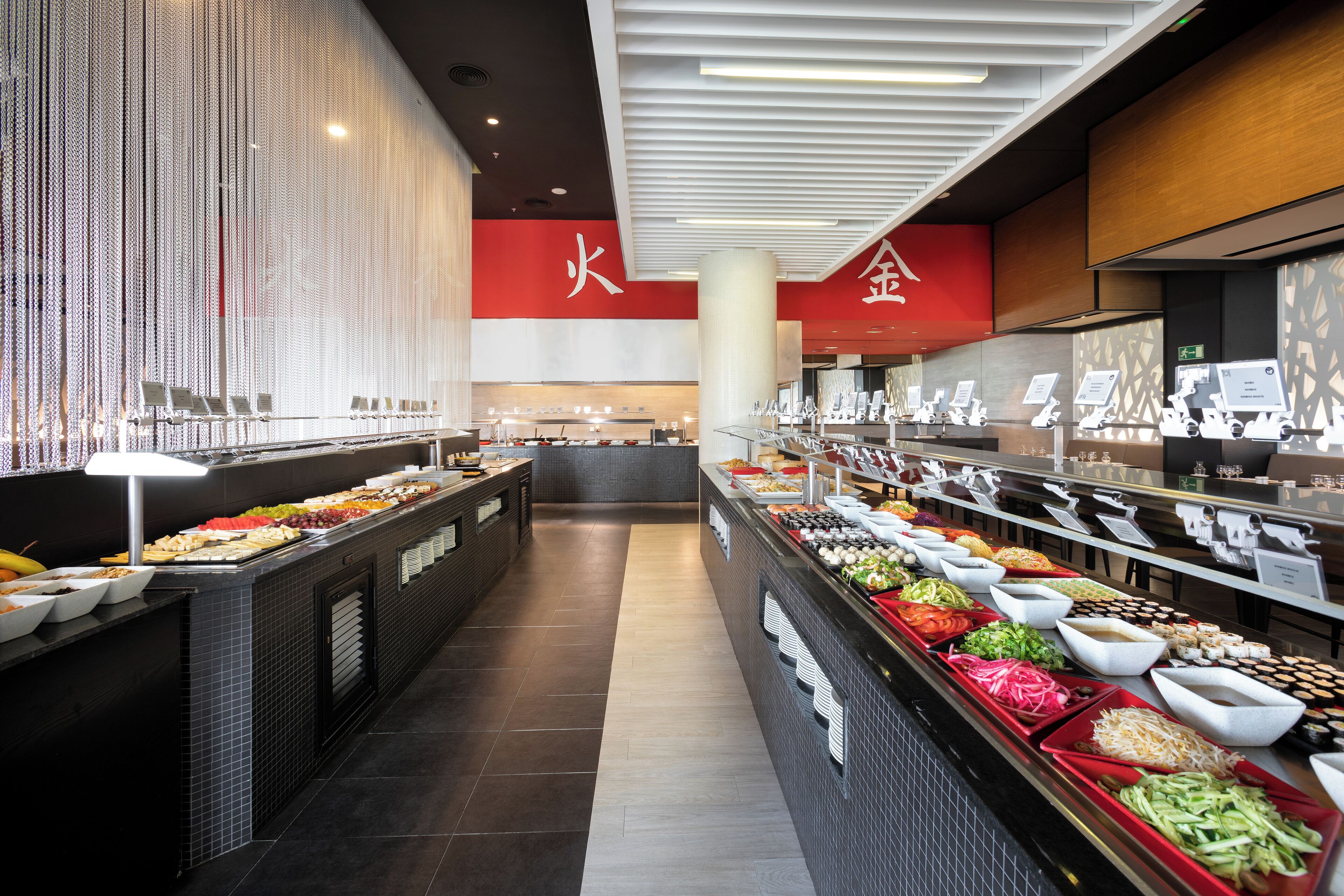 A buffet with various food items and a seating area in the background.